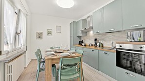 A modern kitchen with light blue cabinets, a wooden dining table, and a built-in oven. - Diamond Lake Apartment 13918 (Angera)
