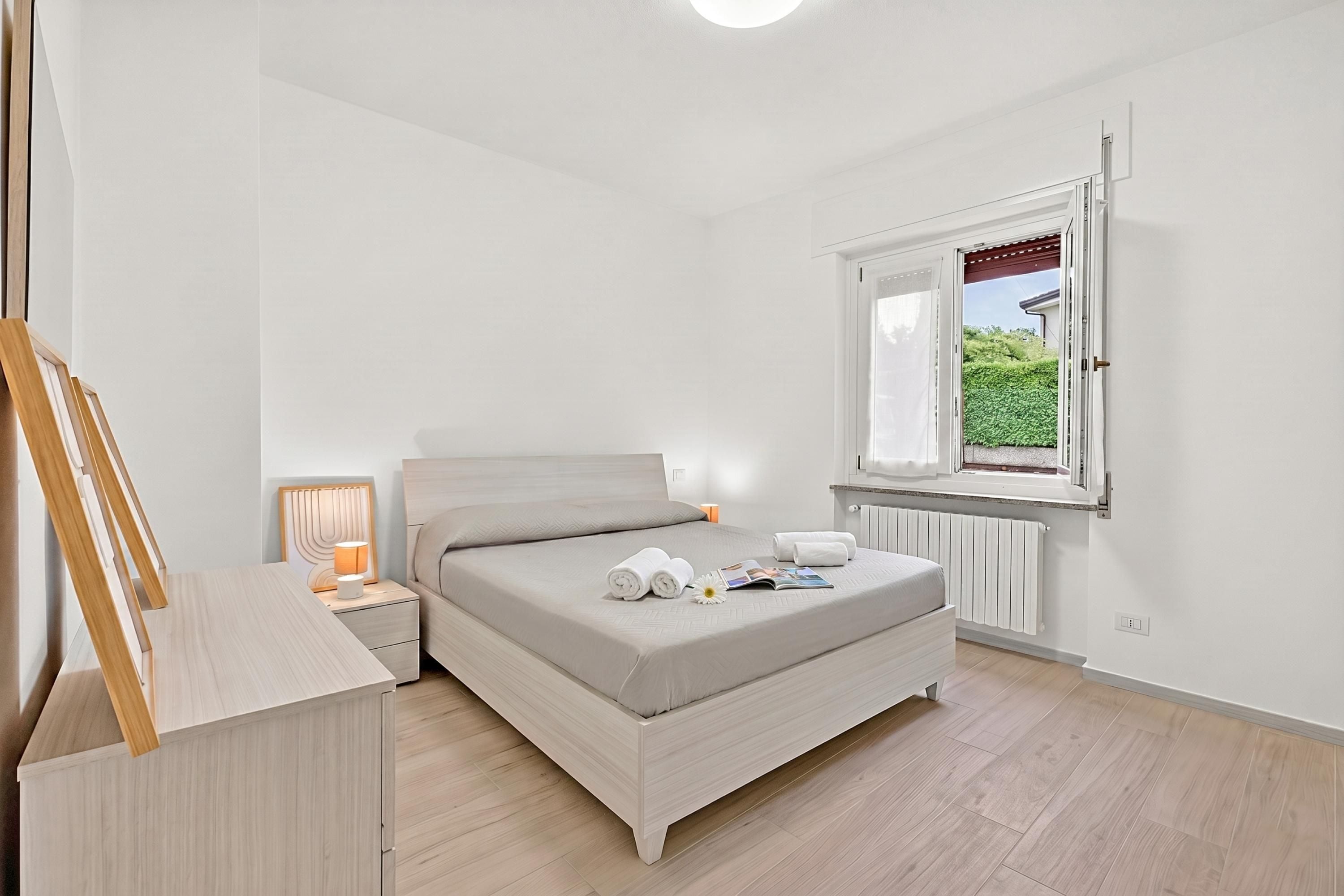 Une chambre à coucher avec un lit, une table de chevet, une lampe et une fenêtre.