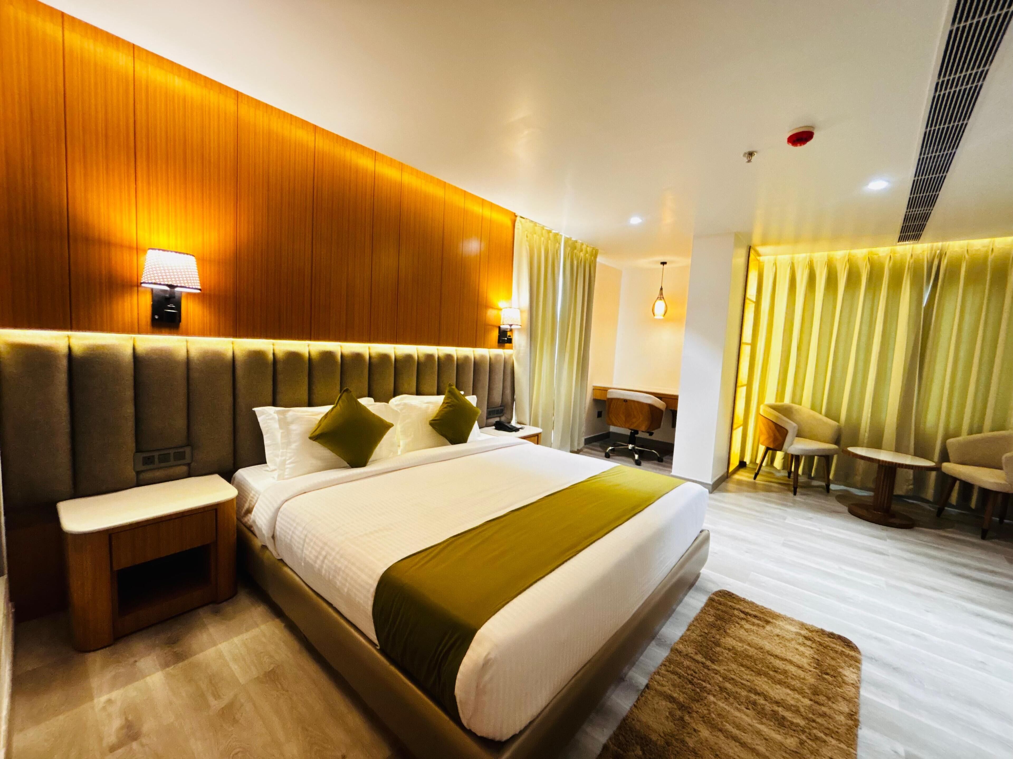 Une chambre d’hôtel avec un grand lit, des tables de chevet, un bureau et une chaise.