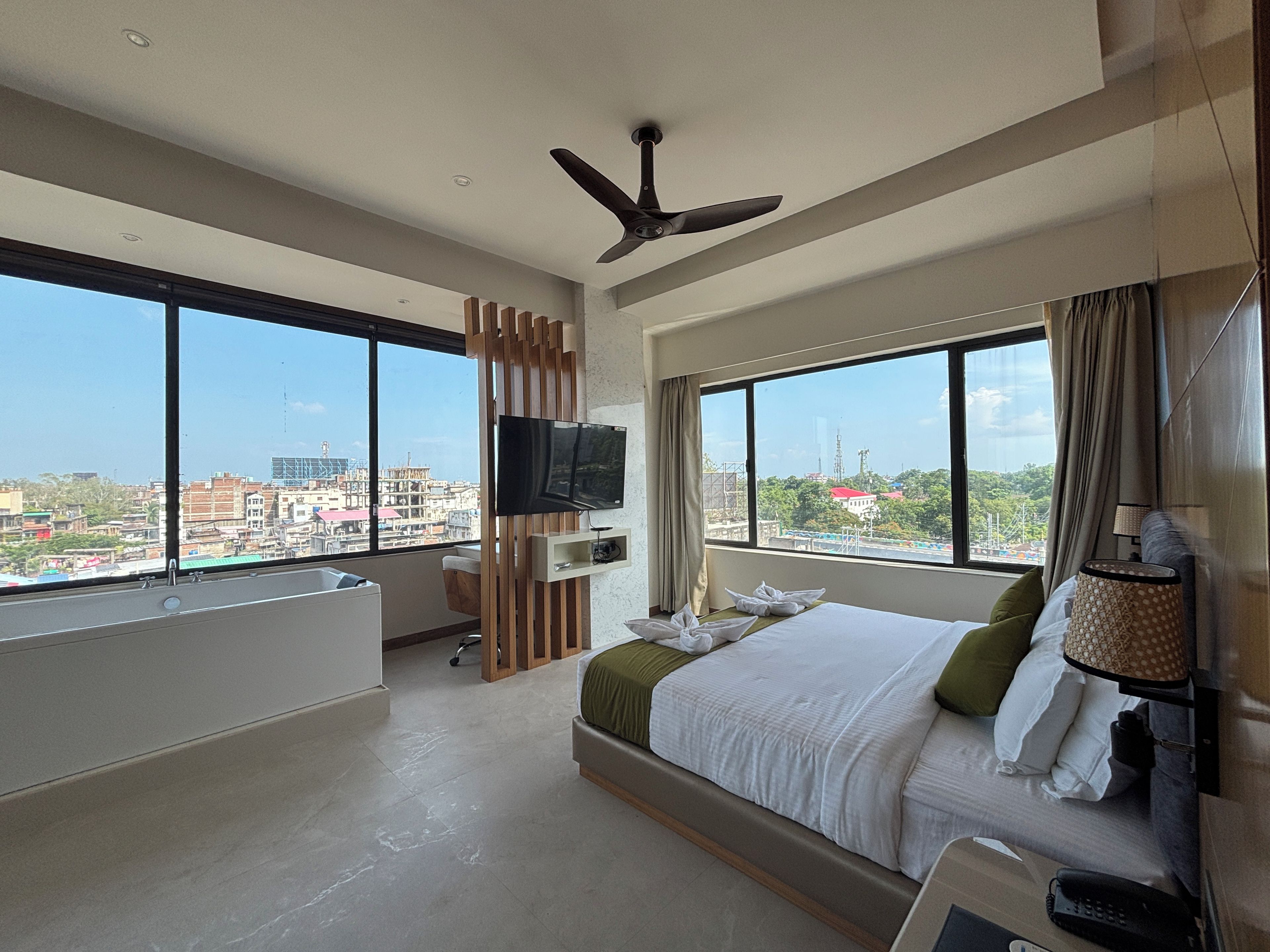 A modern hotel room with a large bed, a TV, and a city view.