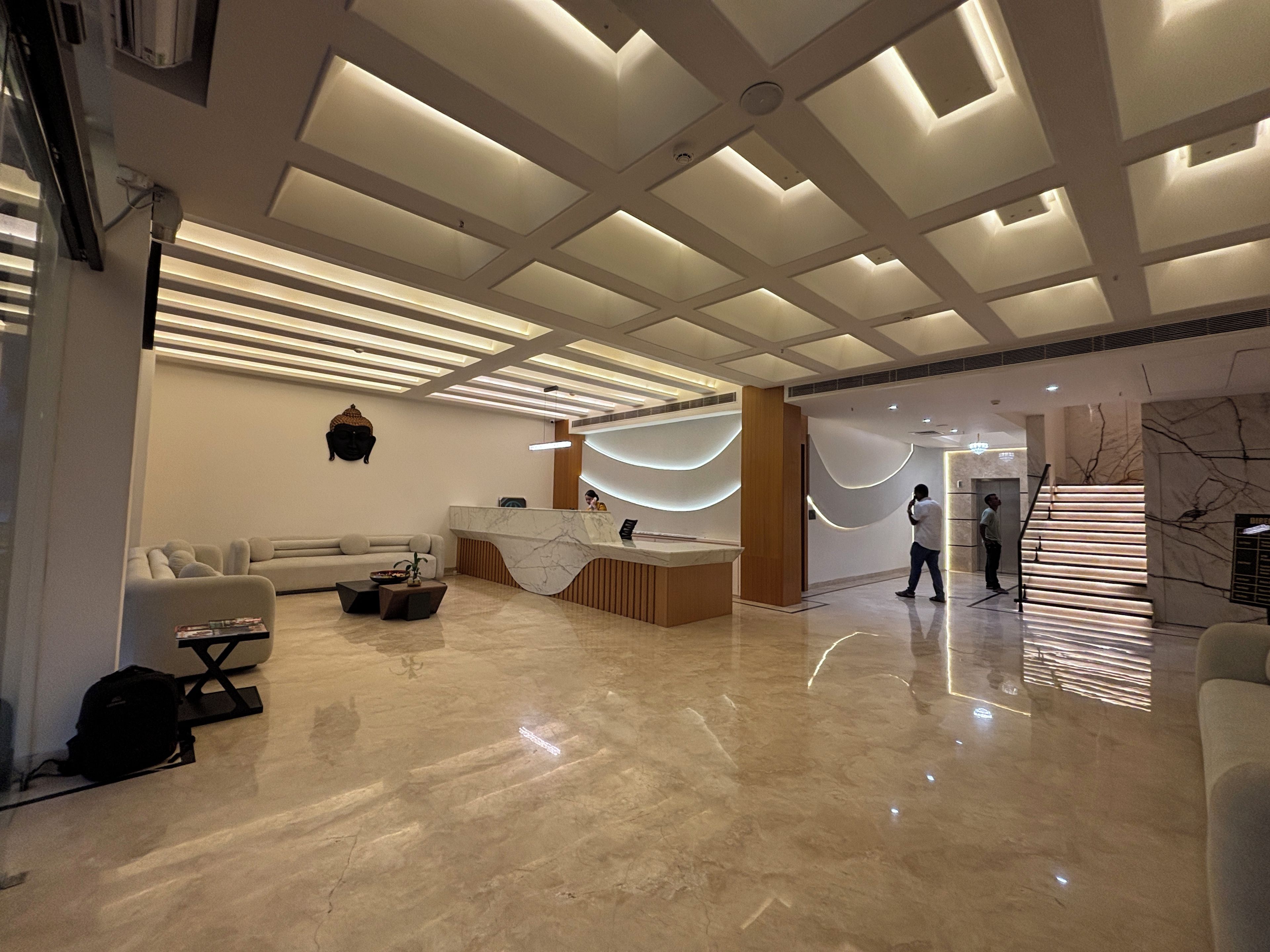 A modern reception area with a marble reception desk, a sofa, and a staircase.