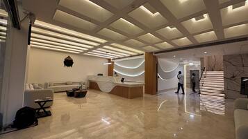 A modern reception area with a marble reception desk, a sofa, and a staircase.