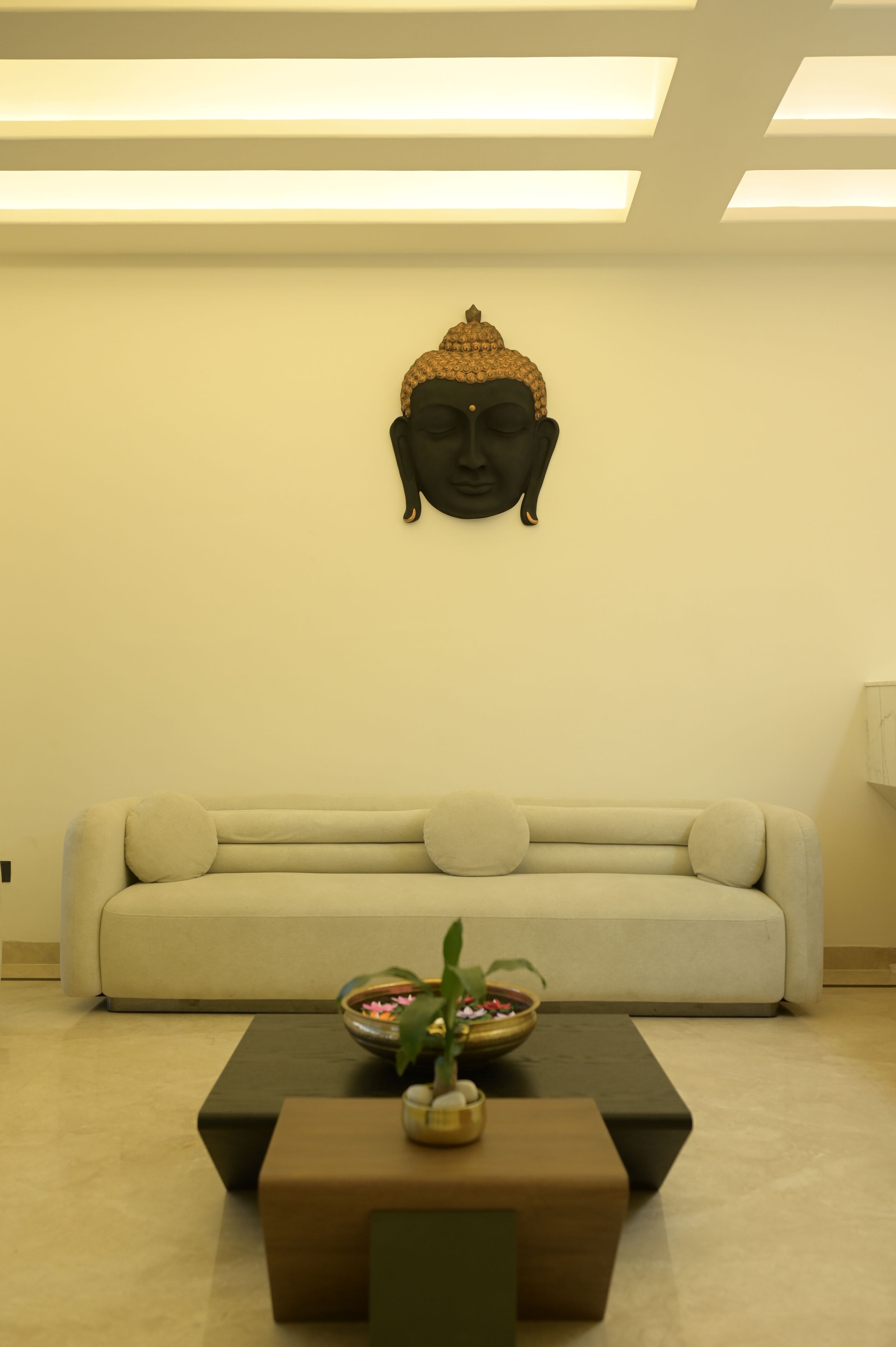 Une pièce comprenant un canapé, une table basse et une statue de Bouddha fixée au mur.