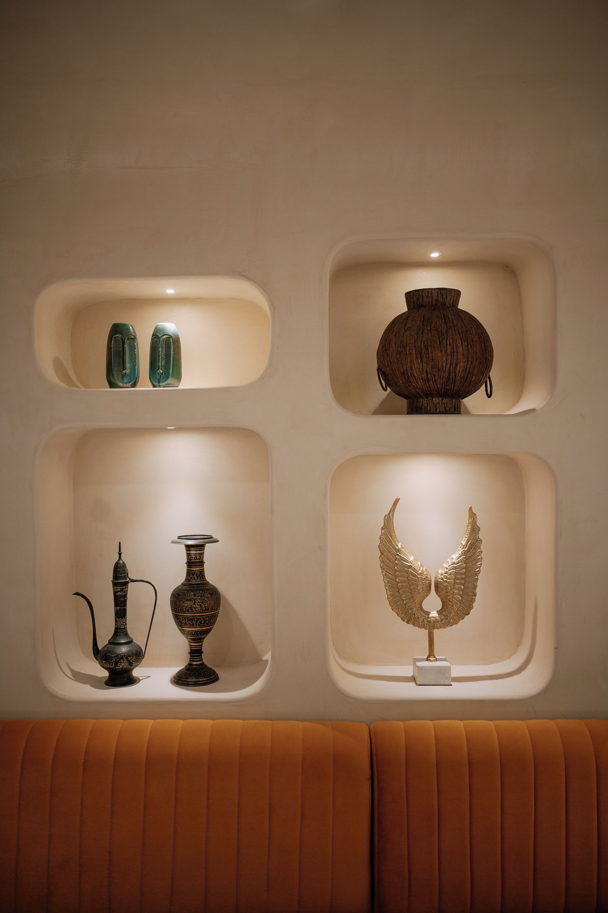 A wall with four recessed shelves displaying various decorative items.