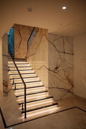 Una escalera con paredes de mármol e iluminación.