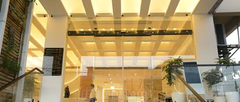 A hotel entrance with a modern design, featuring a glass facade, a staircase leading up to the entrance, and a signboard with important information.