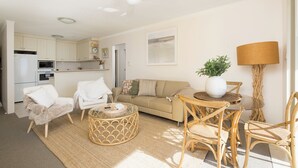 A modern living room with a sofa, chairs, a coffee table, and a dining area with chairs and a table. - Bella Vista Shoal Bay (Shoal Bay)
