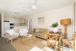 Ein modernes Wohnzimmer mit einer Couch, Sesseln, einem Couchtisch und einem Essbereich mit Stühlen und einem Tisch.