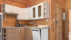 A compact kitchen with wooden cabinetry, a built-in dishwasher, and a coffee maker. - 2 bedroom gorgeous home in Dominikowo (Dominikowo)