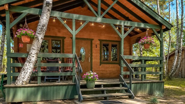 Eine Holzhütte mit Veranda, Tür und Fenster.