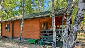 A wooden cabin with a porch, surrounded by trees. - 2 bedroom gorgeous home in Dominikowo (Dominikowo)