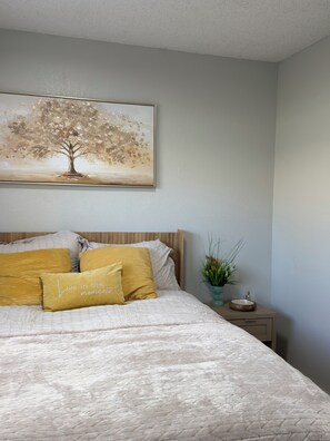 A bedroom with a bed, pillows, a nightstand, a vase with flowers, and a painting on the wall. - 3-bedroom House w/private pool - Family & Pet Friendly (Sacramento)