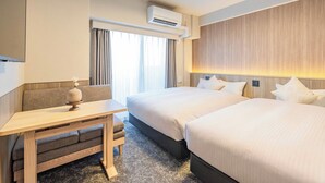 Habitación de hotel con dos camas, un escritorio y zona de estar.