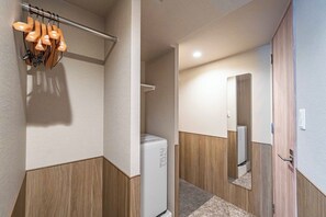 A modern bathroom with a white washing machine, wooden paneling, and a mirror. - Apartment Hotel 11 Dotonbori 10 (Osaka)