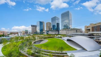 A modern urban landscape with high-rise buildings, a central green park, and a distinctive curved architectural feature.