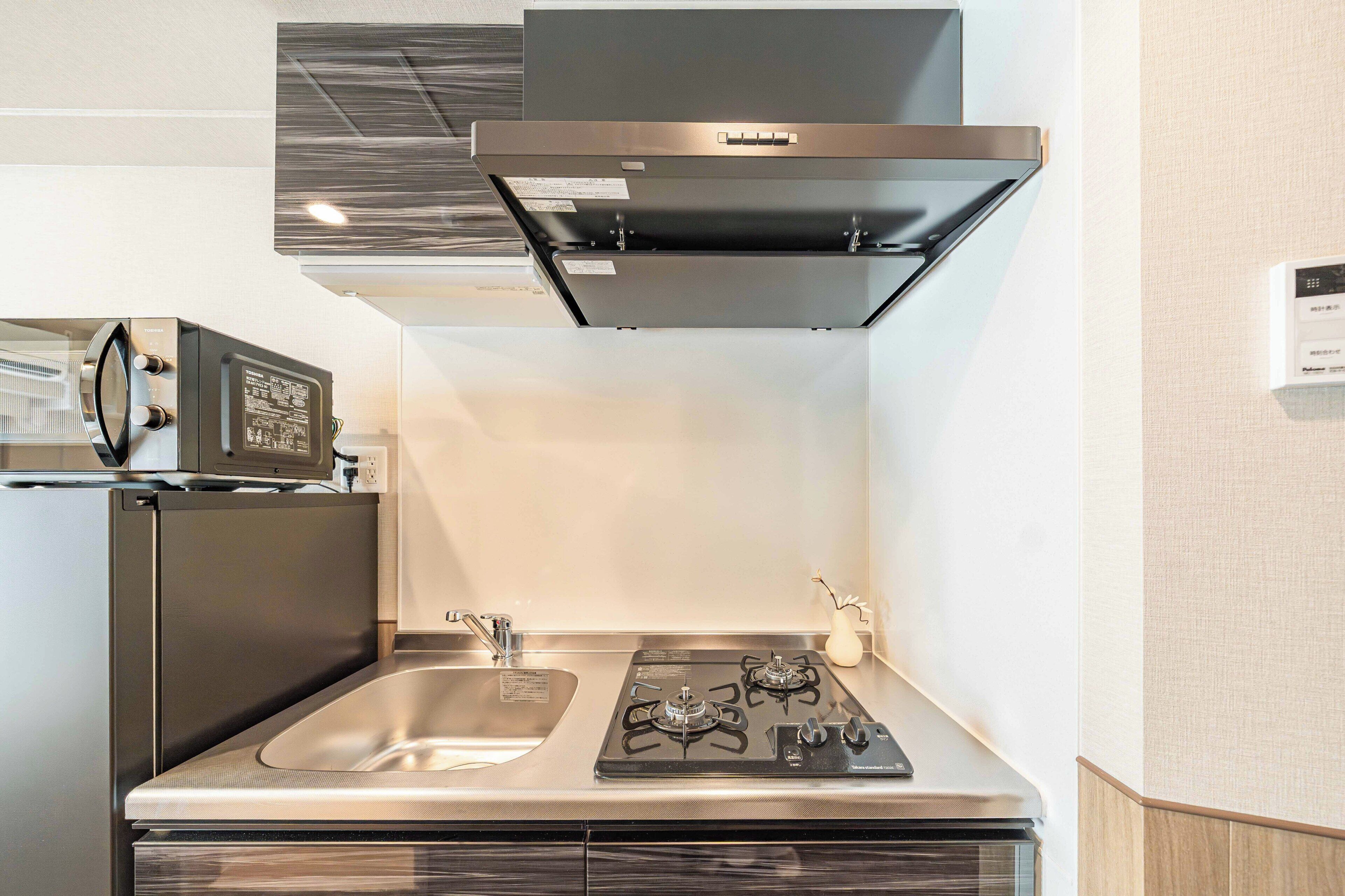Une cuisine compacte équipée d’une cuisinière intégrée, d’un four à micro-ondes et d’un évier.