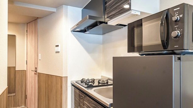Una cocina compacta equipada con microondas, estufa a gas y refrigerador.