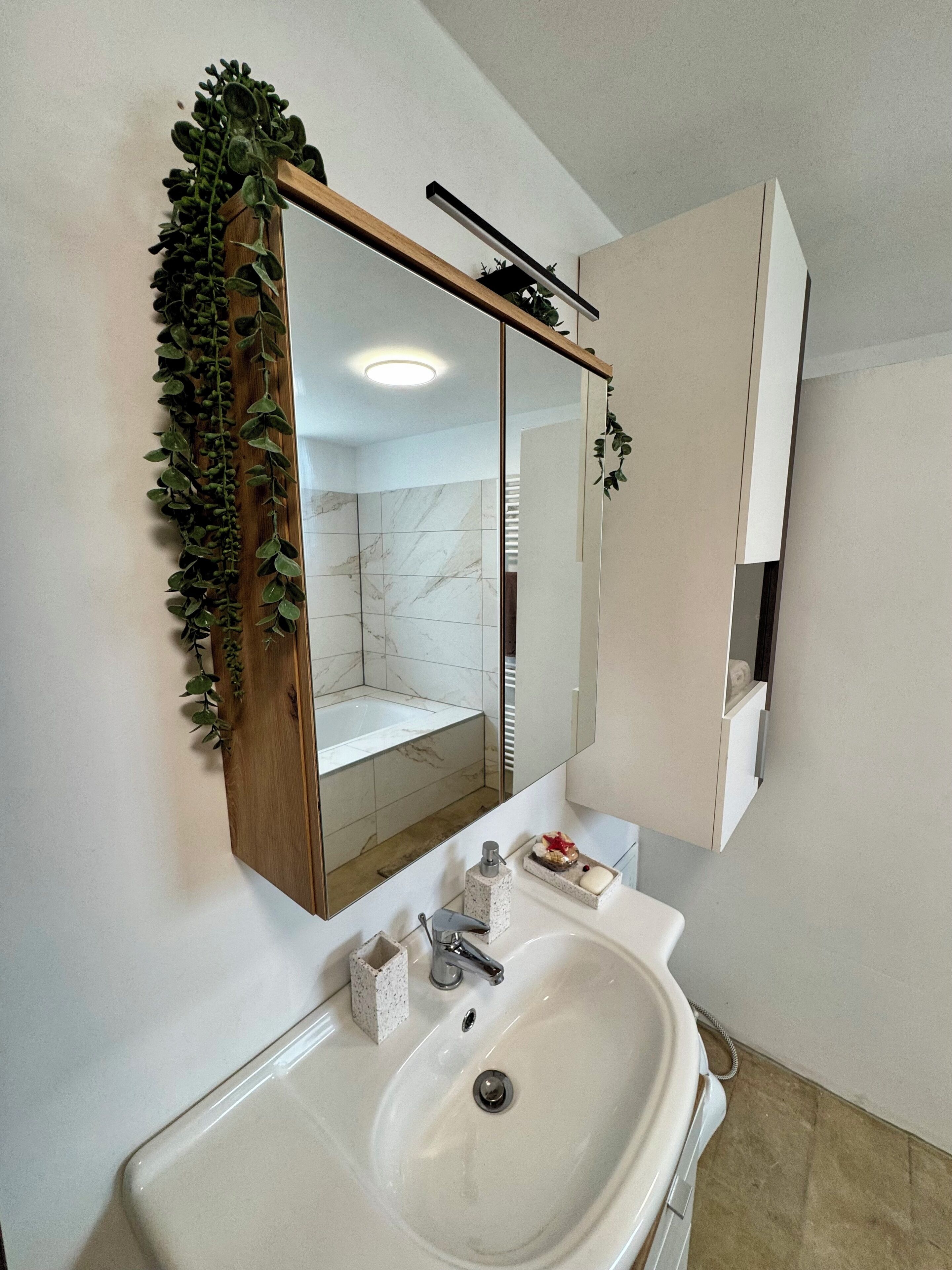 A bathroom with a large mirror, a sink, and a shower area.