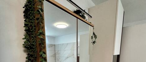 A bathroom with a large mirror, a sink, and a shower area.