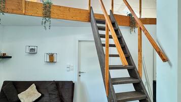 A modern interior with a wooden staircase, a dark brown sofa, and a skylight.