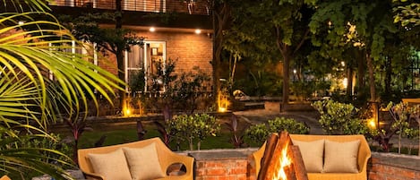 An outdoor seating area with wicker furniture and a central fire pit.