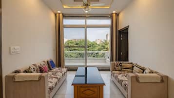 A room with two sofas facing a large window, a central table, and a ceiling fan.
