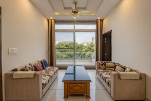 A room with two sofas facing a large window, a central table, and a ceiling fan.