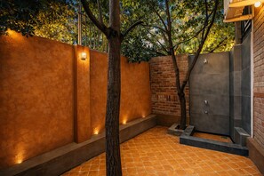 A spa area with a brick wall, a tree, and a tiled floor. - Private Luxury Farm House Estate with gaming room (Jaipur)