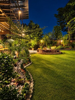 A well-lit outdoor area with a grassy lawn, potted plants, and a brick structure.