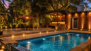 Ein rechteckiger Swimmingpool mit Fliesenrand, umgeben von einer Ziegelmauer und einer Holzterrasse.