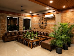 A spacious living room with a leather sofa, wooden coffee table, and potted plants.
