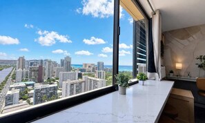 A modern interior with a large window overlooking a cityscape and the ocean. - Waikiki 2BR 2BA 34th Fl Ocean View Sunset/Sunrise (Honolulu)