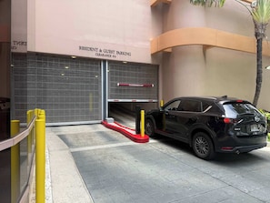 A black SUV parked in a gated parking area with a sign indicating 'RESIDENT & GUEST PARKING CLEARANCE 6-6'. - Waikiki 2BR 2BA 34th Fl Ocean View Sunset/Sunrise (Honolulu)