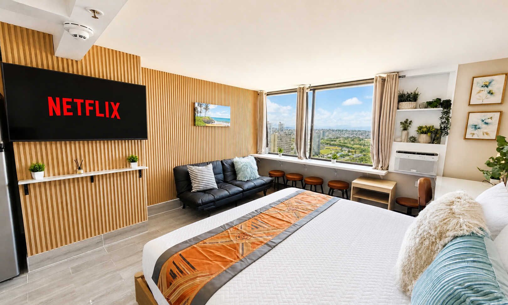 Habitació d'hotel moderna amb un llit gran, un sofà, un escriptori i una televisió penjada a la paret.