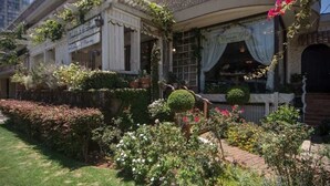 A traditional building with a garden in front, featuring a variety of plants and flowers. - Waikiki 2BR 2BA 34th Fl Ocean View Sunset/Sunrise (Honolulu)