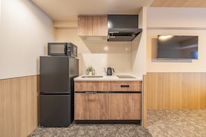 Eine kleine Küche mit Kühlschrank, Mikrowelle, Spüle und Holzschränken.