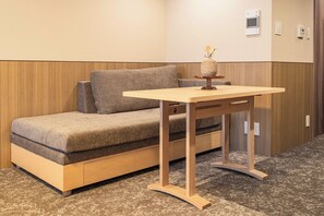 Ein Zimmer mit einer Couch, einem kleinen Holztisch und einer Blumenvase.