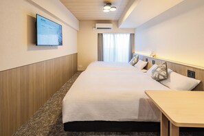 Ein Hotelzimmer mit Bett, Nachttisch, an der Wand montiertem Fernseher, Klimaanlage und einem Fenster mit Vorhängen.