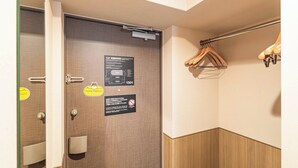 A hotel room with a wooden door, a towel rack, and a notice about the evacuation route. - Apartment Hotel 11 Hanazono 1 (Osaka-shi)