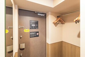 Ein Hotelzimmer mit Holztür, Handtuchhalter und einer Information über den Evakuierungsweg.