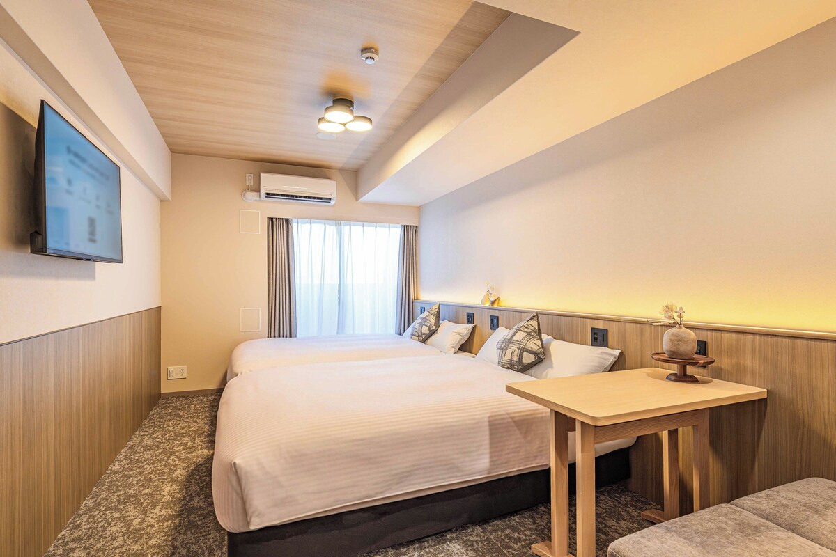 Ein Hotelzimmer mit einem Bett, einem Schreibtisch und einem an der Wand befestigten Fernseher.