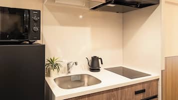 A modern kitchen with a built-in microwave, a kettle, and a sink.