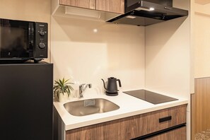 A modern kitchen with a built-in microwave, a kettle, and a sink. - Apartment Hotel 11 Hanazono 1 (Osaka-shi)