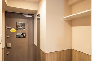 Habitació d'hotel amb una porta de fusta, una petxina penjada a la paret i un senyal que marca la ruta d'evacuació.