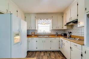A kitchen with white cabinets, a wooden countertop, a built-in stove, and a window with a decorative grille. - Spacious 4BR/2.5BA Pet-Friendly Home in Clayton, NC – Minutes from Raleigh, Sleeps 8 (Clayton)