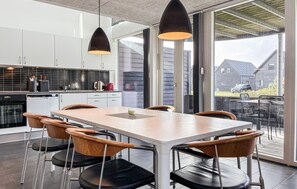 Een moderne keuken met witte kasten, een zwart aanrecht en een eethoek met een tafel en stoelen.