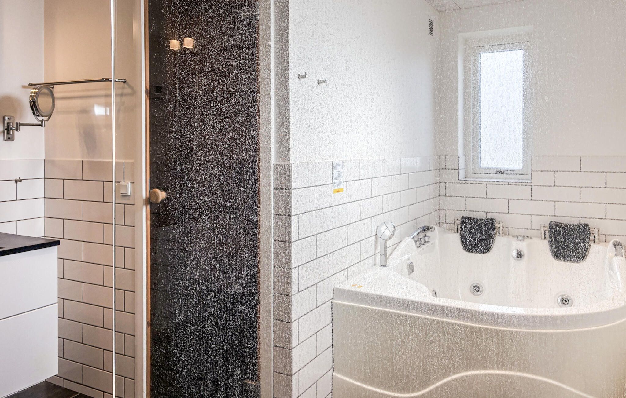 A bathroom with a bathtub, a shower area, and a window.