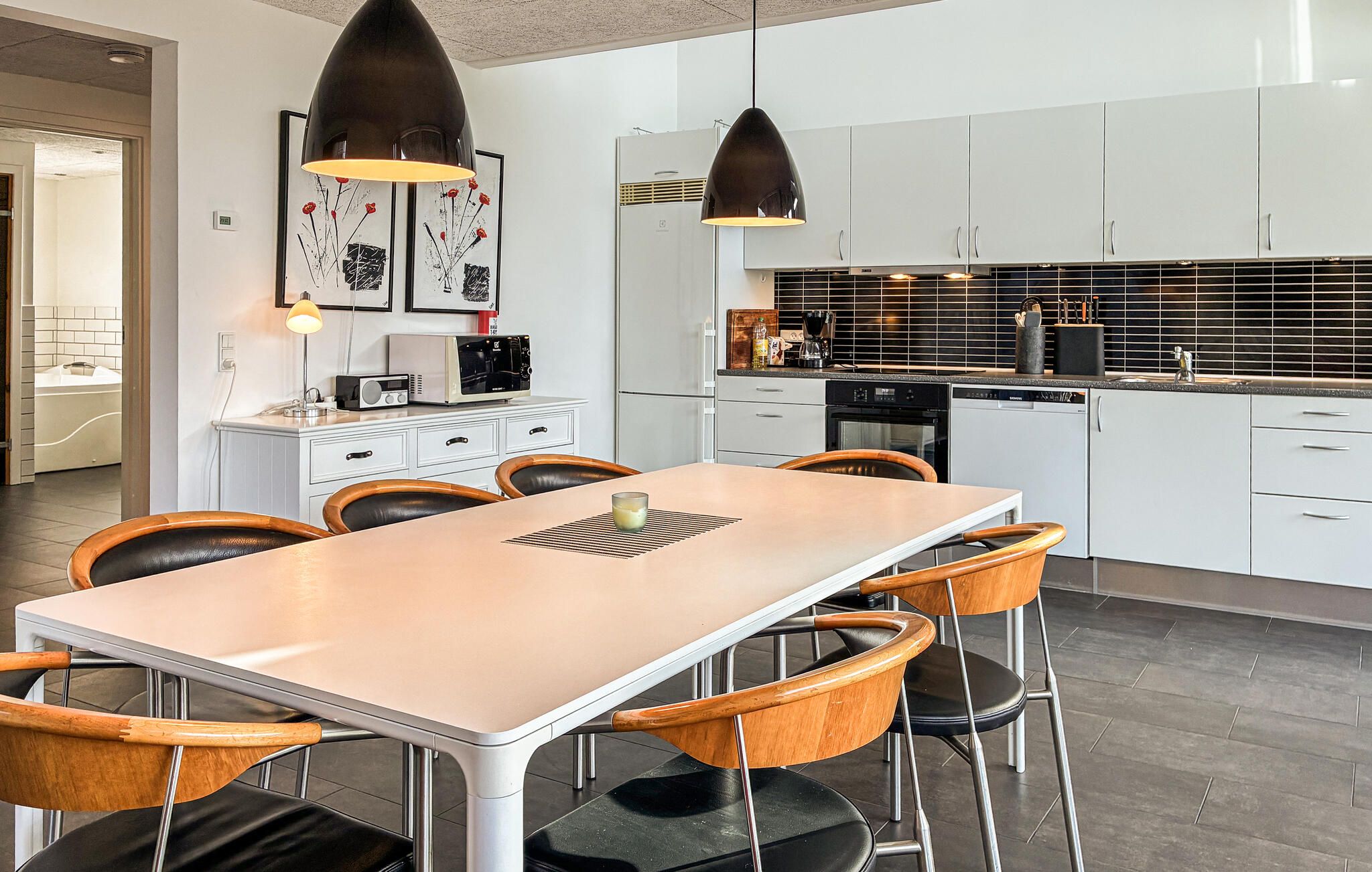 A modern kitchen with white cabinets, a central island, and pendant lighting.