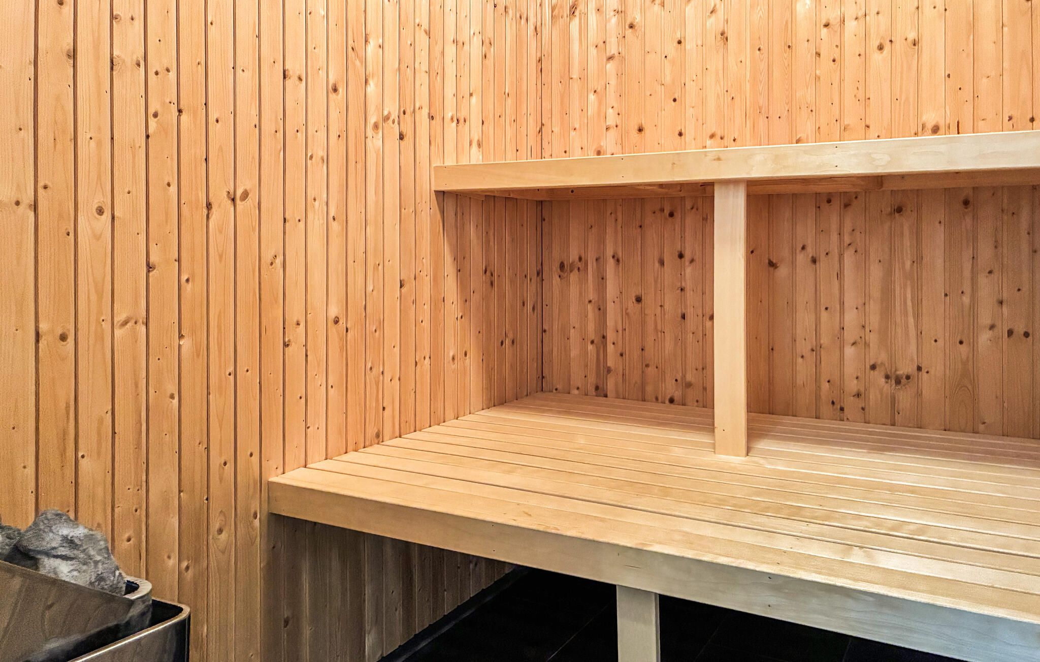 Eine Holzsauna mit einer Sitzbank und einem Mülleimer.