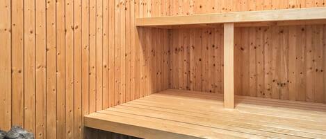 Een houten sauna met een bank en een prullenbak.
